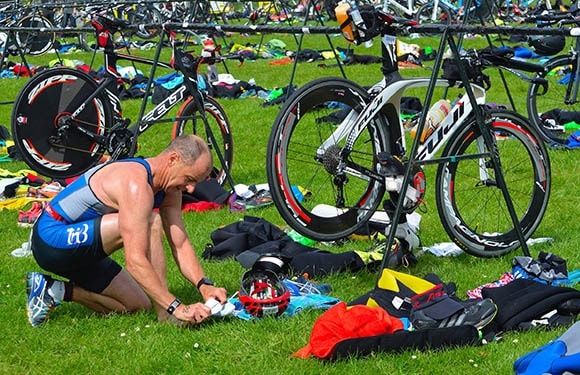 Triathlet organiserar utrustning bland cyklar i växlingszonen